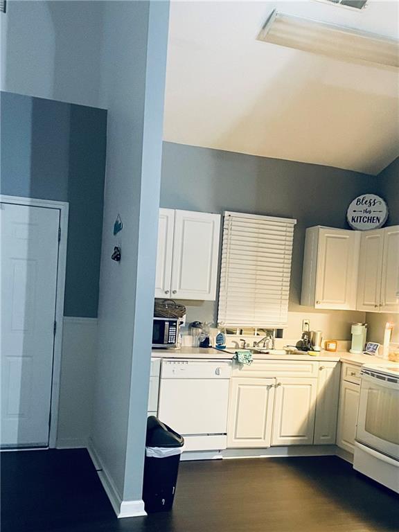 kitchen with white appliances, white cabinets, light countertops, and a sink