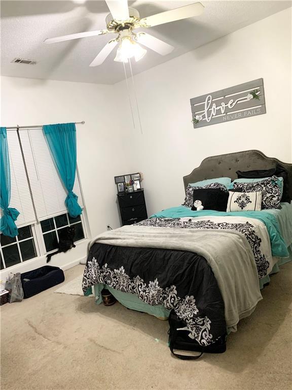 bedroom with a ceiling fan, visible vents, and carpet floors