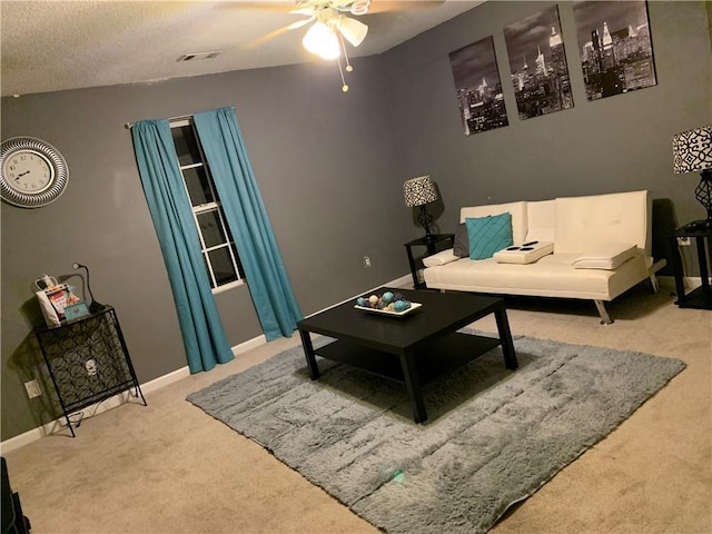 living area with visible vents, a ceiling fan, a textured ceiling, carpet flooring, and baseboards
