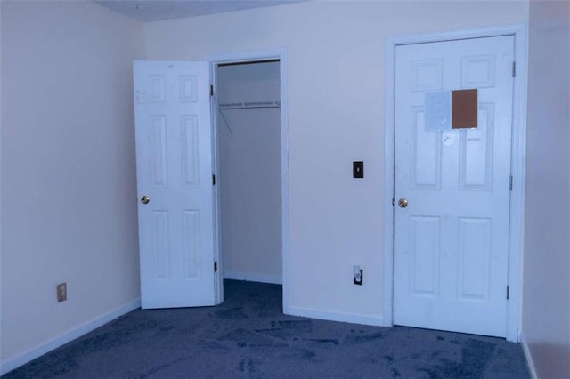 unfurnished bedroom with dark carpet and a closet