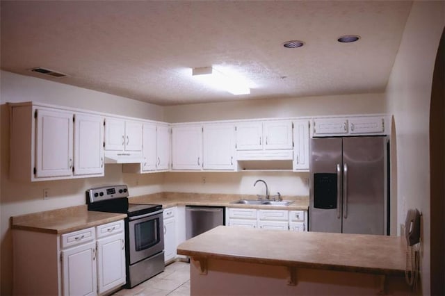 kitchen featuring sink, light tile patterned floors, white cabinets, and appliances with stainless steel finishes