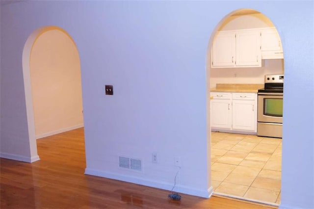 kitchen featuring white cabinetry, light hardwood / wood-style floors, and electric range