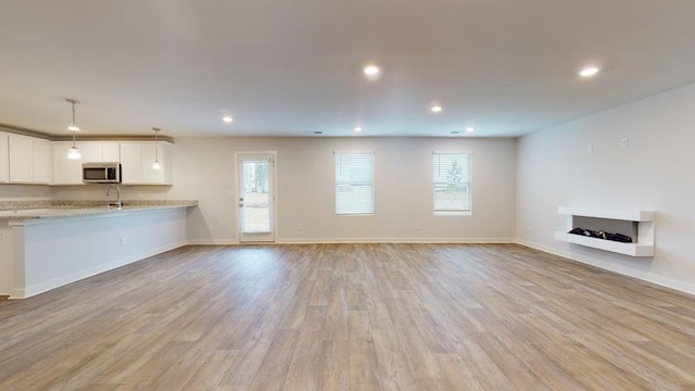 142 Post Oak Dr, Jackson, GA 30233 - unfurnished living room featuring plenty of natural light, recessed lighting, light wood finished floors, baseboards, and a fireplace with raised hearth