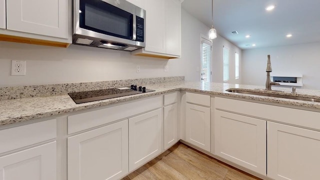142 Post Oak Dr, Jackson, GA 30233 - kitchen with stainless steel microwave, black electric cooktop, a sink, white cabinets, and light wood finished floors