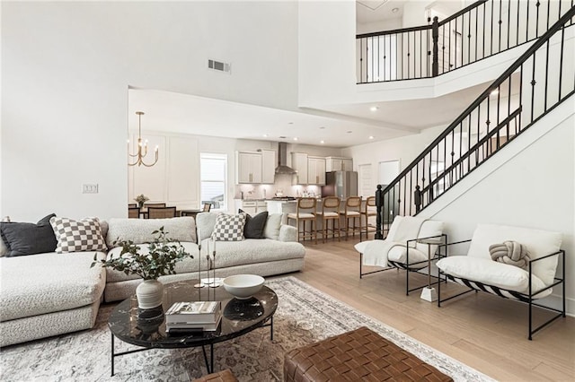 7985 Welch Ml, Ball Ground, GA 30107 - living room with a high ceiling, light wood finished floors, stairs, and a chandelier