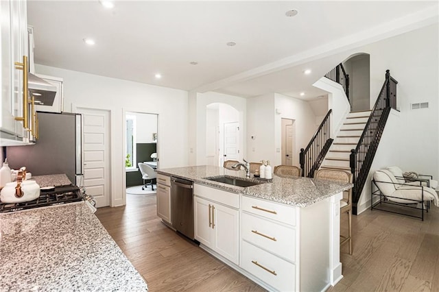 7985 Welch Ml, Ball Ground, GA 30107 - kitchen featuring stainless steel appliances, a sink, arched walkways, wood finished floors, and a breakfast bar area