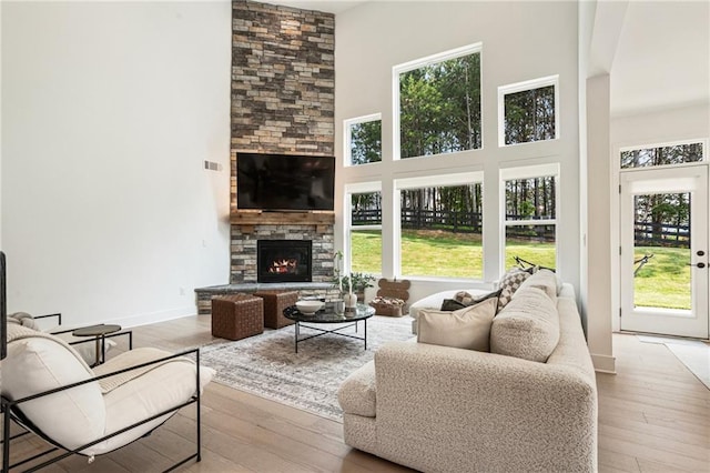7985 Welch Ml, Ball Ground, GA 30107 - living area featuring a towering ceiling, a fireplace, hardwood / wood-style flooring, and baseboards