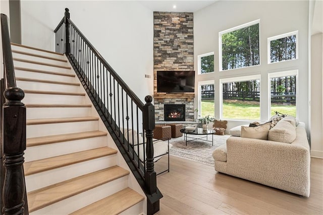 7985 Welch Ml, Ball Ground, GA 30107 - living room featuring healthy amount of natural light, a fireplace, a high ceiling, stairs, and wood finished floors