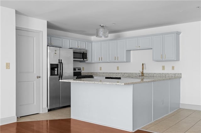 1102 Madison Ln SE Unit 1102, Smyrna, GA 30080 - kitchen with appliances with stainless steel finishes, a peninsula, light stone counters, and light wood-style flooring