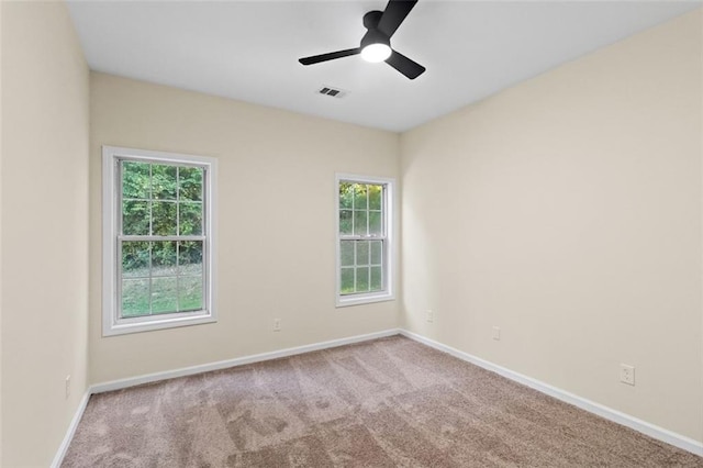 carpeted empty room featuring ceiling fan, visible vents, and baseboards