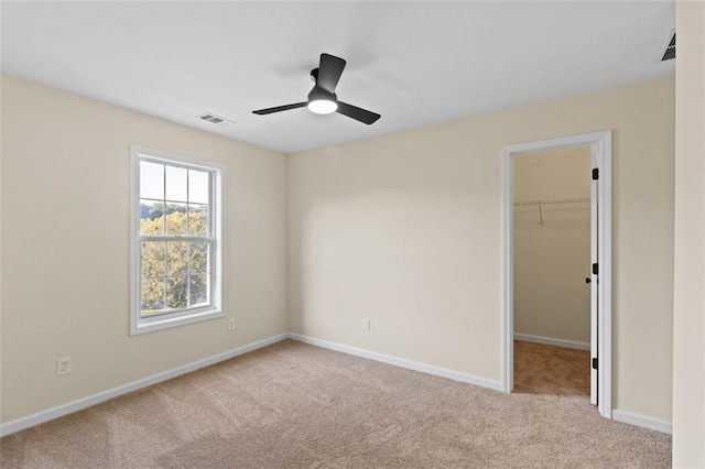 carpeted empty room with ceiling fan, visible vents, and baseboards