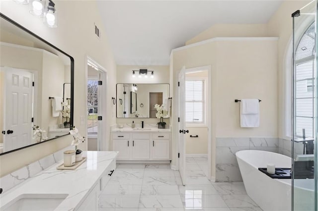 bathroom featuring visible vents, lofted ceiling, marble finish floor, a freestanding bath, and vanity