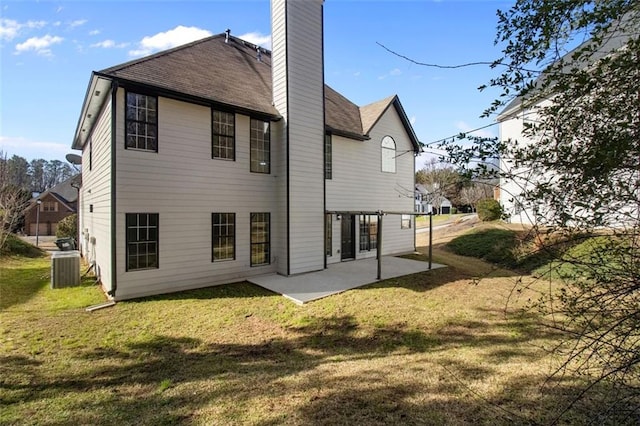 rear view of property featuring a chimney, a lawn, a patio area, and cooling unit