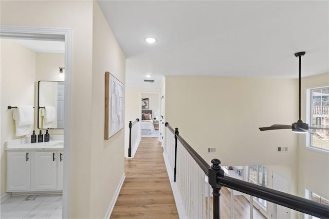 corridor featuring light wood-style floors, baseboards, visible vents, and recessed lighting