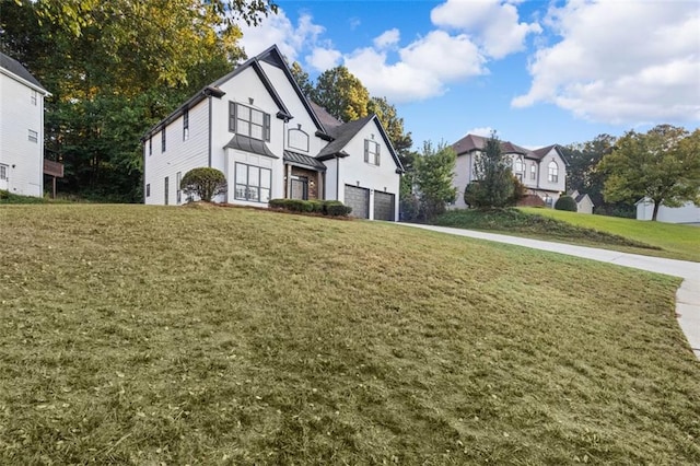 view of front facade with a garage, a standing seam roof, driveway, and a front lawn