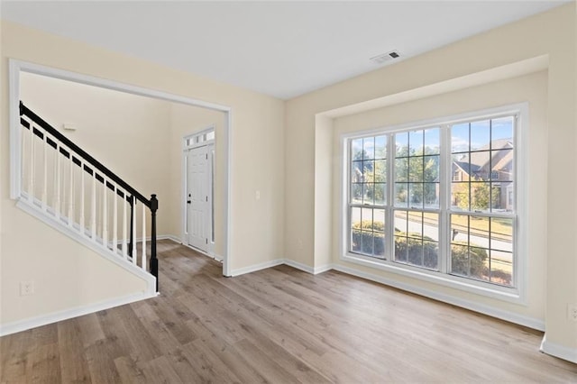 entrance foyer with baseboards, stairs, visible vents, and wood finished floors