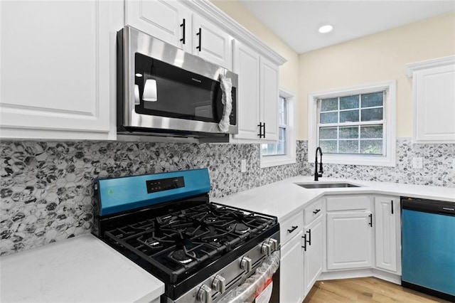 kitchen featuring stainless steel appliances, a sink, white cabinets, light countertops, and tasteful backsplash