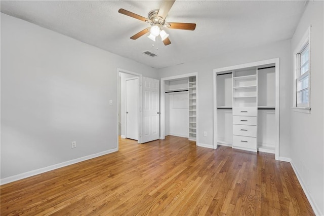 unfurnished bedroom with two closets, ceiling fan, and light hardwood / wood-style floors