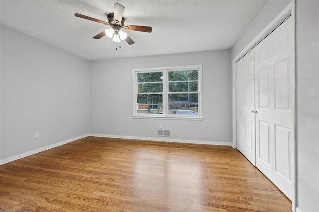 unfurnished bedroom featuring light hardwood / wood-style floors, a closet, and ceiling fan