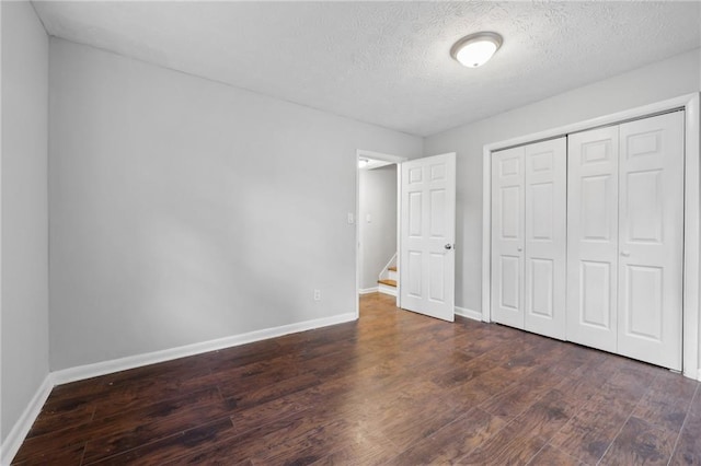 unfurnished bedroom with a closet, dark hardwood / wood-style floors, and a textured ceiling