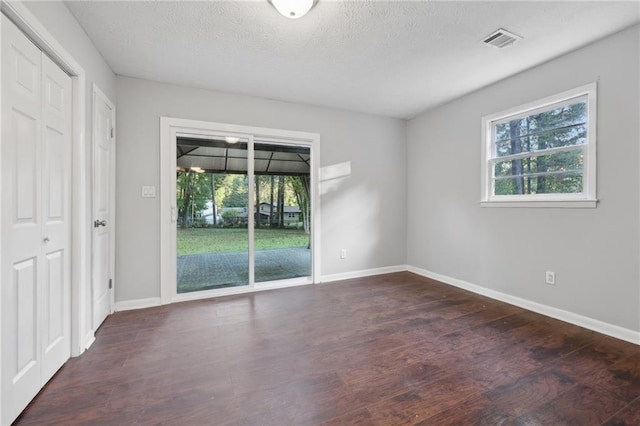 spare room with dark wood-type flooring and a textured ceiling