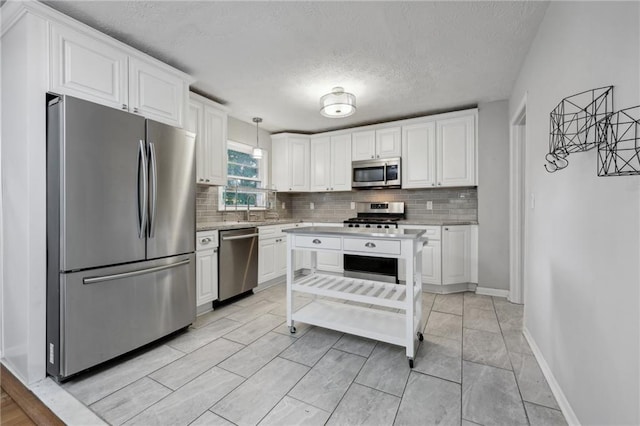 kitchen featuring stainless steel appliances, pendant lighting, and white cabinets