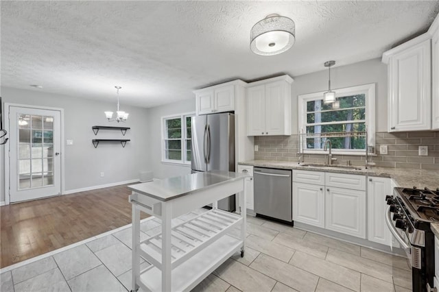 kitchen featuring tasteful backsplash, sink, white cabinets, hanging light fixtures, and stainless steel appliances