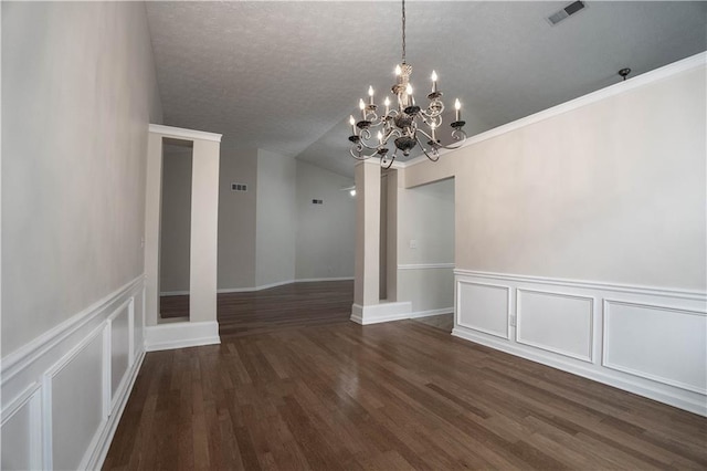 empty room with a textured ceiling, dark hardwood / wood-style floors, and a chandelier