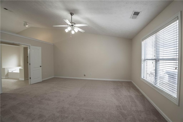 carpeted spare room with ceiling fan, a textured ceiling, and vaulted ceiling