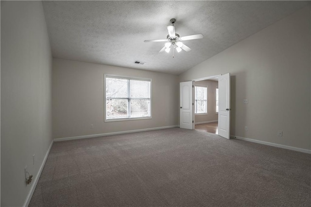 unfurnished room with lofted ceiling, ceiling fan, dark carpet, and a textured ceiling