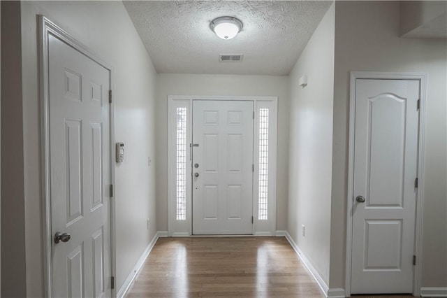 entryway with light wood-type flooring, a textured ceiling, and a healthy amount of sunlight