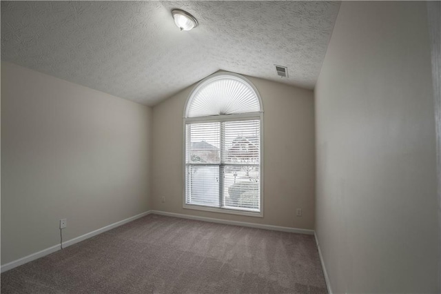 carpeted spare room featuring a textured ceiling and lofted ceiling