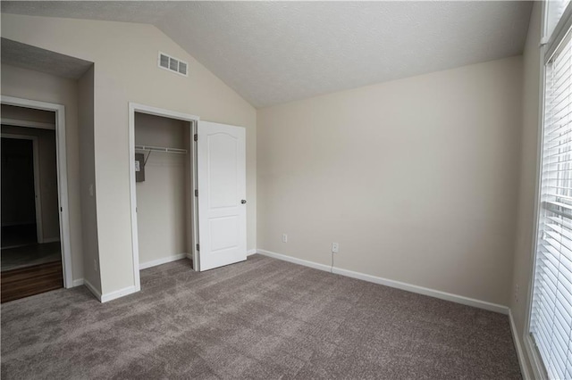 unfurnished bedroom with a closet, vaulted ceiling, and carpet flooring