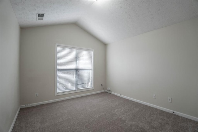 carpeted empty room with a textured ceiling and vaulted ceiling