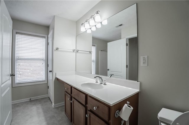 bathroom featuring toilet, plenty of natural light, and vanity