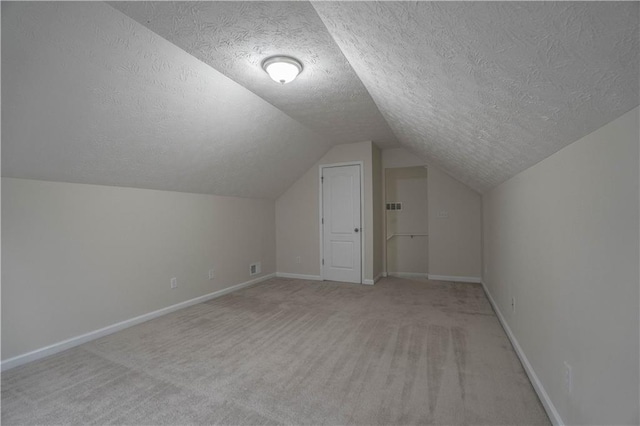 additional living space featuring light colored carpet, a textured ceiling, and vaulted ceiling