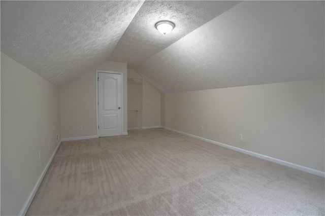 bonus room featuring light carpet, vaulted ceiling, and a textured ceiling