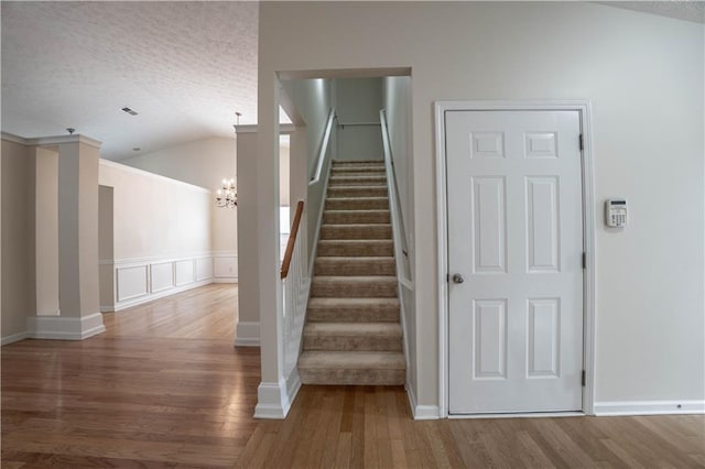 staircase featuring wood-type flooring, lofted ceiling, and a notable chandelier