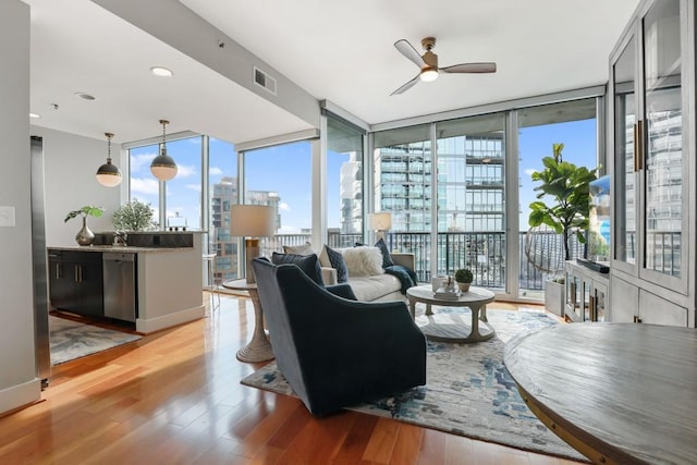 living room featuring expansive windows, a healthy amount of sunlight, visible vents, and light wood-style floors