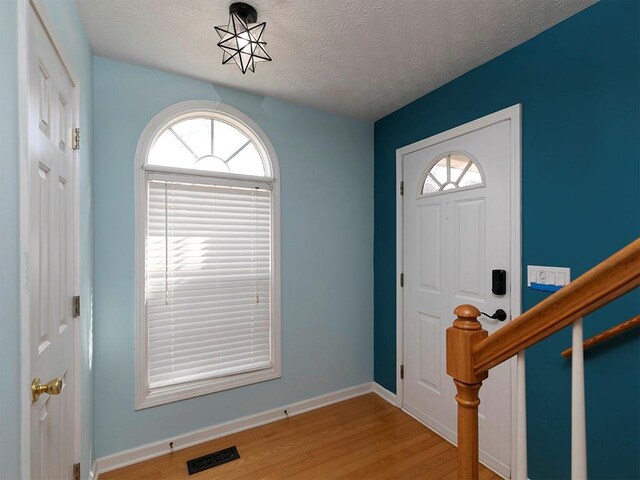 spare room with a notable chandelier, a wealth of natural light, and light hardwood / wood-style floors