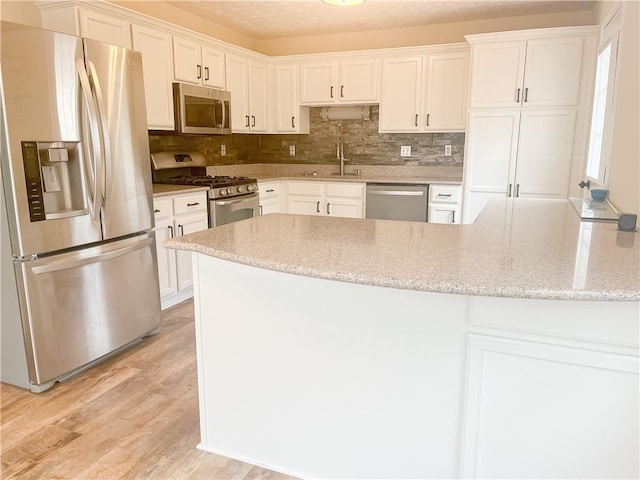 kitchen featuring light stone counters, stainless steel appliances, and white cabinets