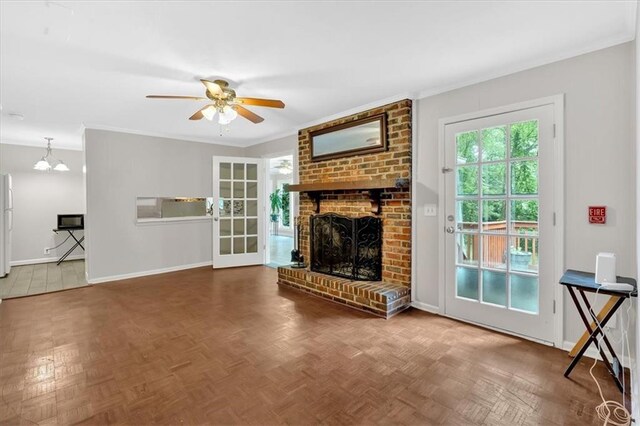 unfurnished living room with a brick fireplace, baseboards, ceiling fan, crown molding, and a chandelier