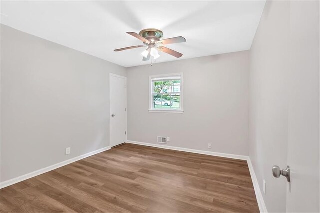 empty room with ceiling fan, baseboards, and wood finished floors