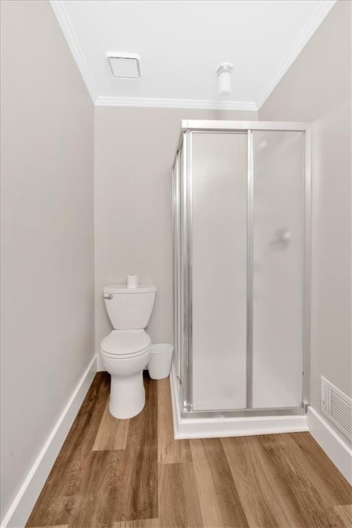full bathroom featuring wood finished floors, ornamental molding, toilet, a shower stall, and baseboards