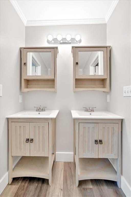bathroom with two vanities, ornamental molding, wood finished floors, and baseboards