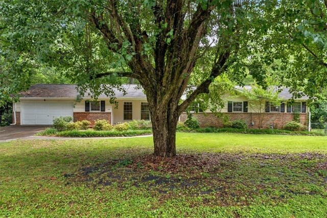 single story home featuring brick siding, an attached garage, a front lawn, and driveway