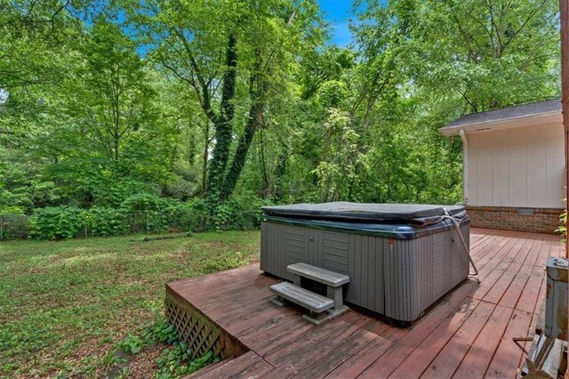 wooden deck with a hot tub and a wooded view
