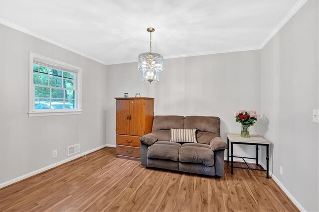 living area with light wood-type flooring, baseboards, crown molding, and a chandelier