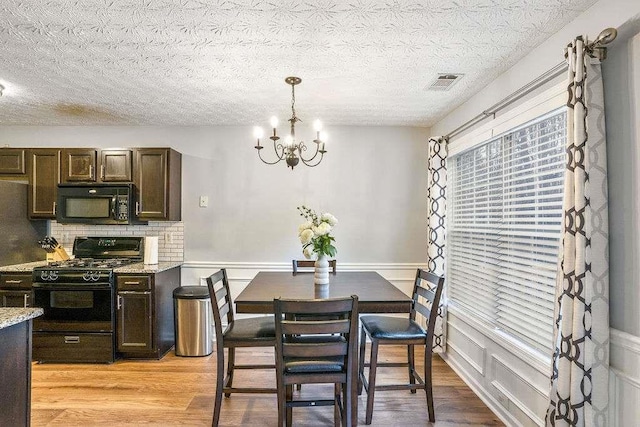 dining room with an inviting chandelier, a textured ceiling, and light wood-type flooring