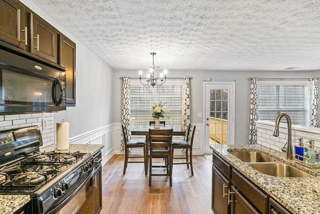 kitchen featuring sink, dark wood-type flooring, plenty of natural light, light stone counters, and black appliances